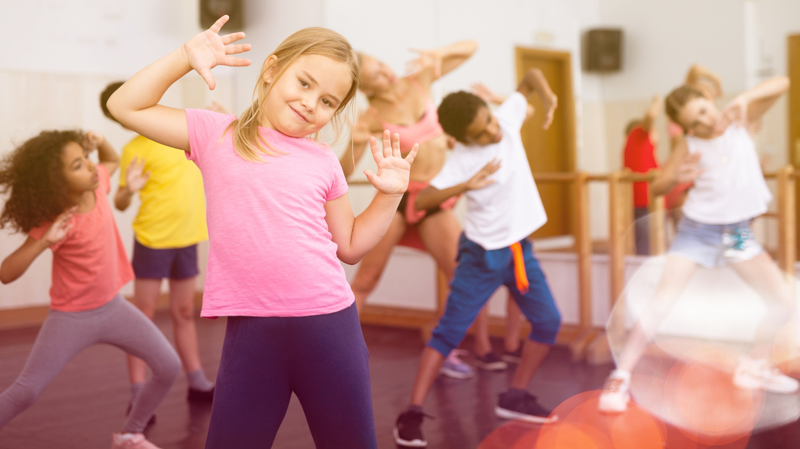 Smiling little girl training vigorous dance in children dance studio